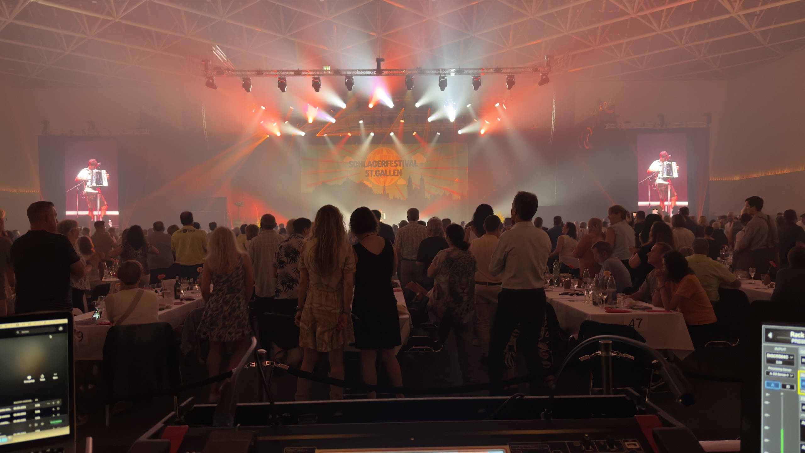 Blick vom FOH-Platz auf eine beleuchtete Festivalbühne und das Publikum